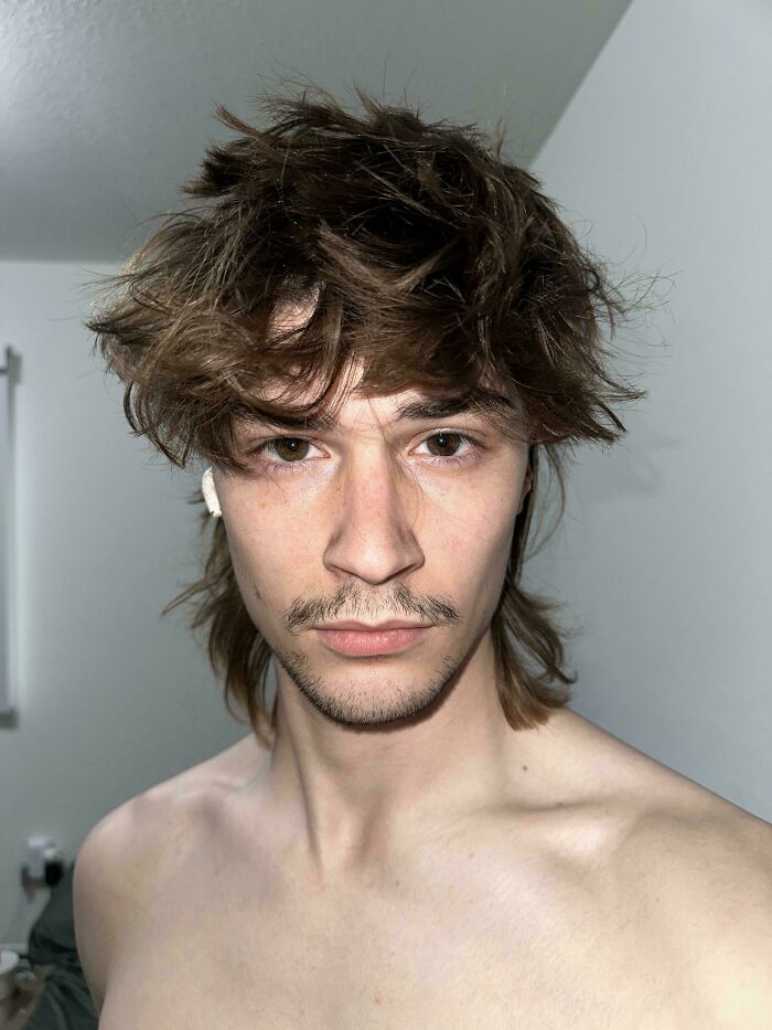 A man with amazing long hair, a mustache, and a slight beard, looking directly at the camera.