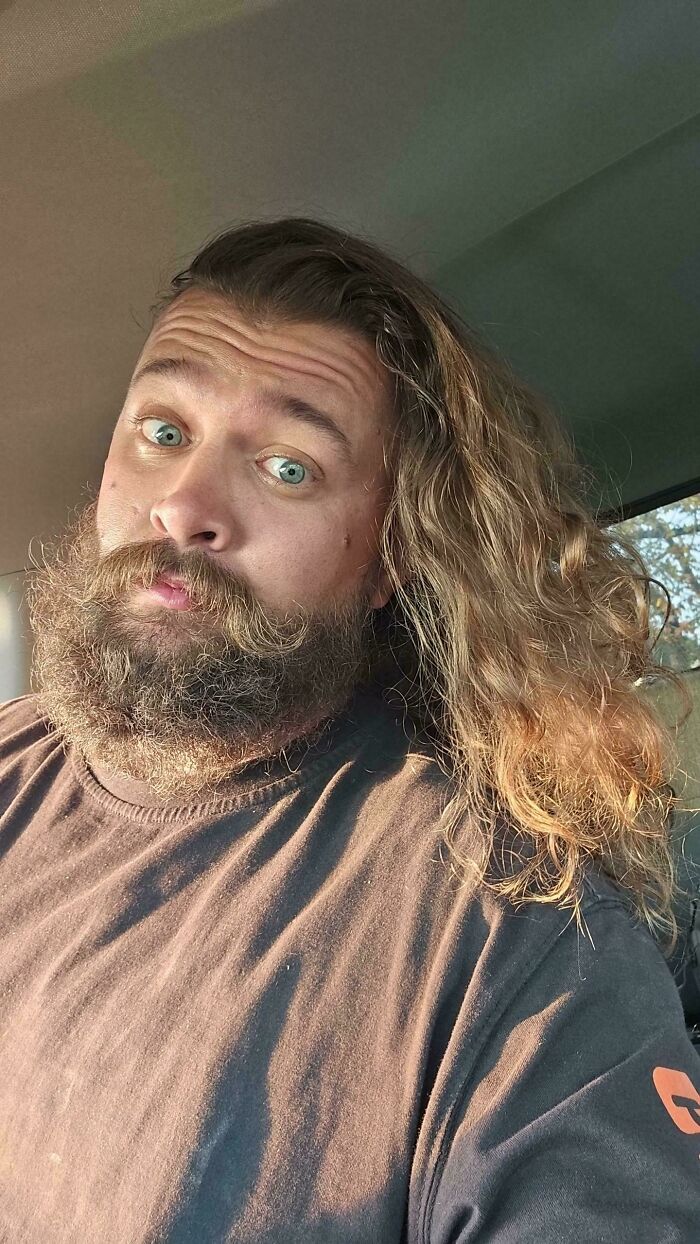 A man with amazing long hair and a full beard with an open mouth expression, looking directly at the camera.