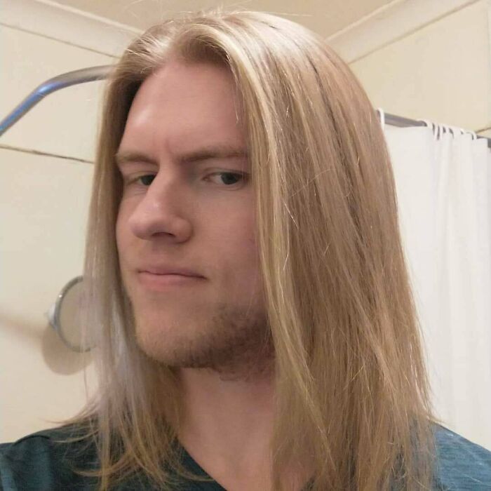 A man with straight, long hair and light stubble, showcasing his amazing long hair.