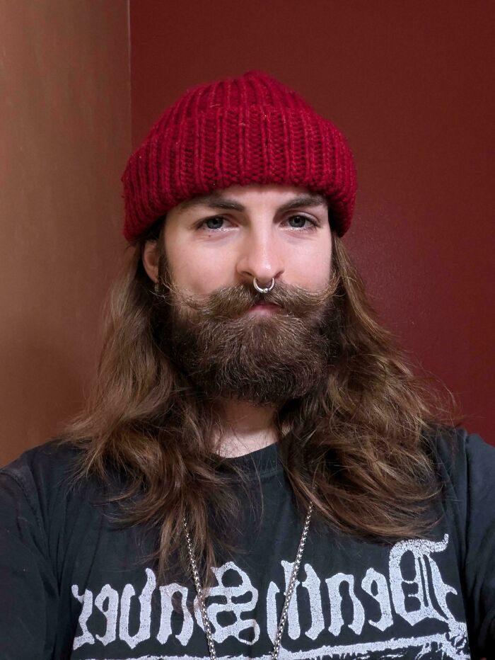 A man with long hair, a beard, and a red beanie, showcasing amazing long hair.