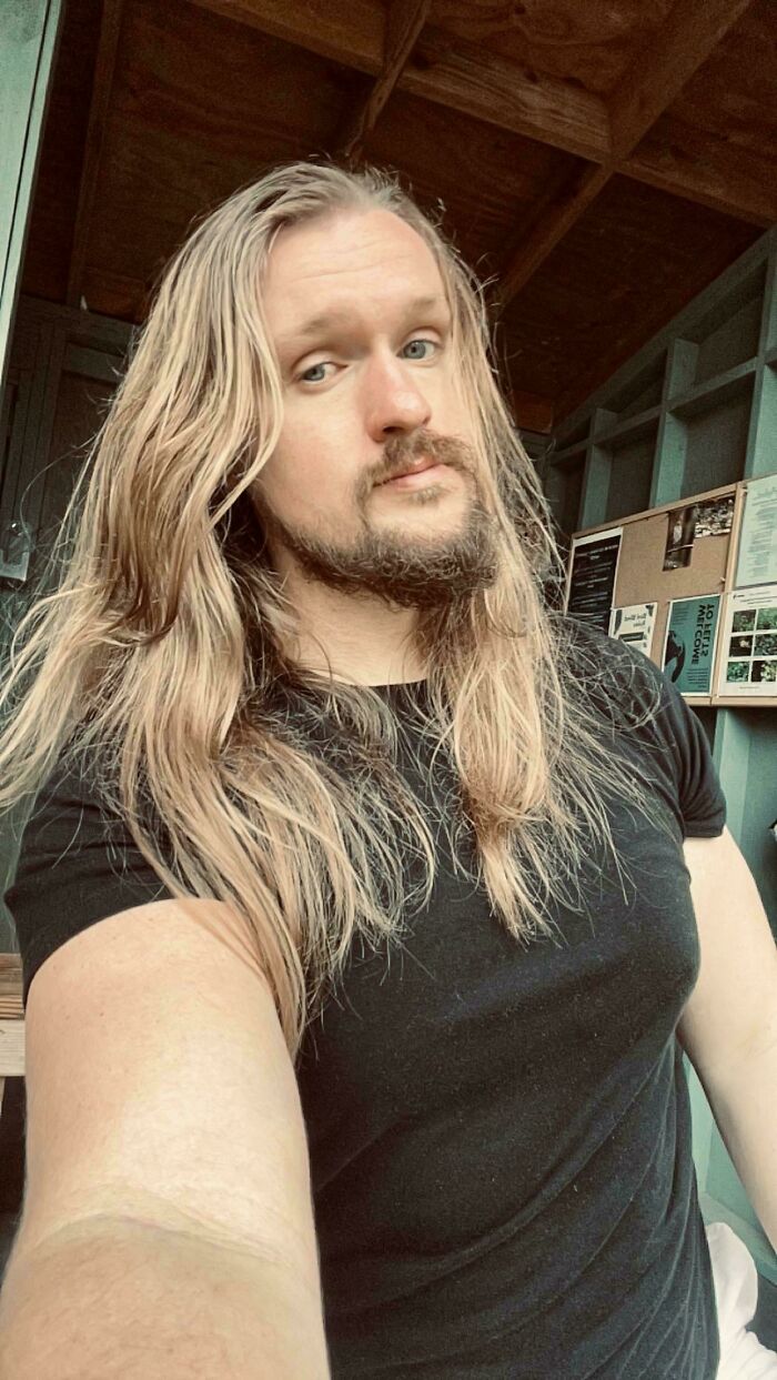 A man with ridiculously amazing long, blonde hair and a beard looks at the camera.