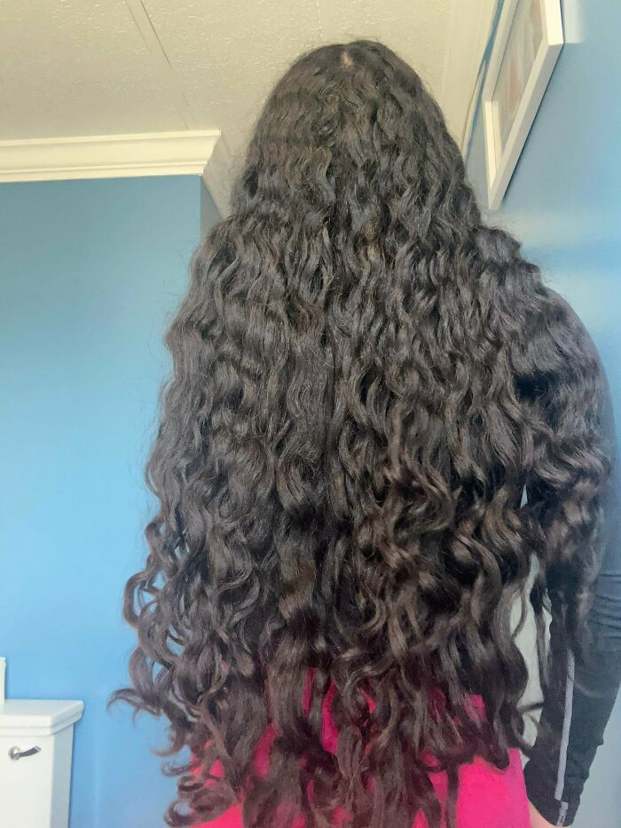 A woman from behind with ridiculously amazing long curly dark hair, cascading down her back.