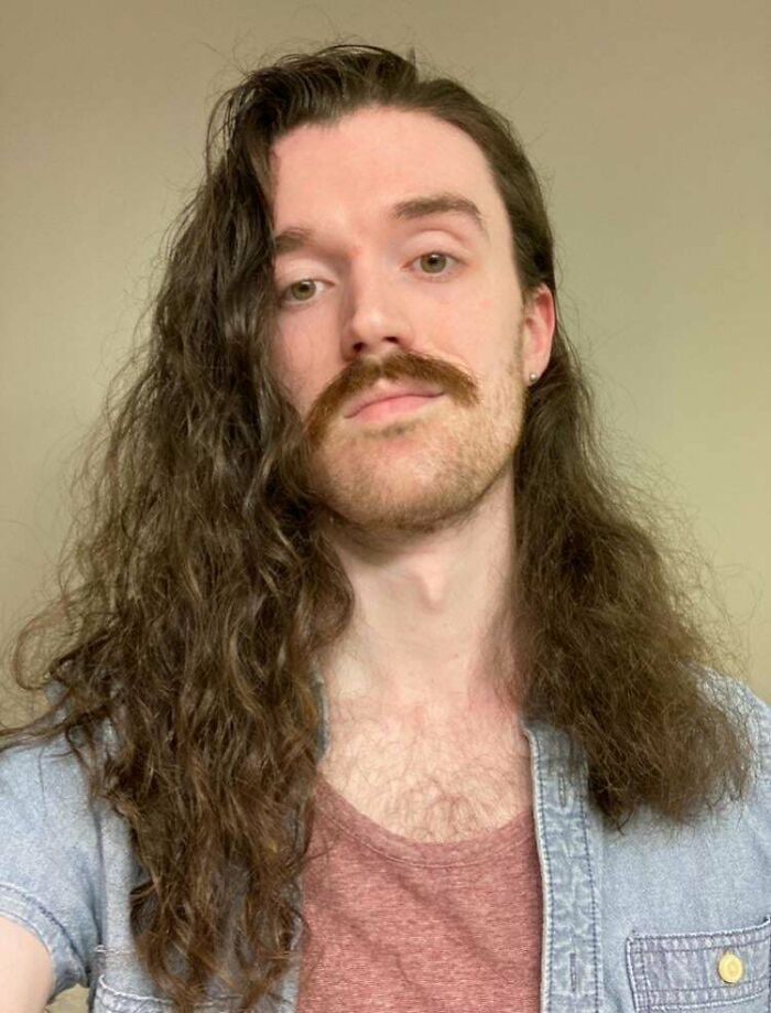 A man with ridiculously amazing long hair and a mustache poses for a picture.