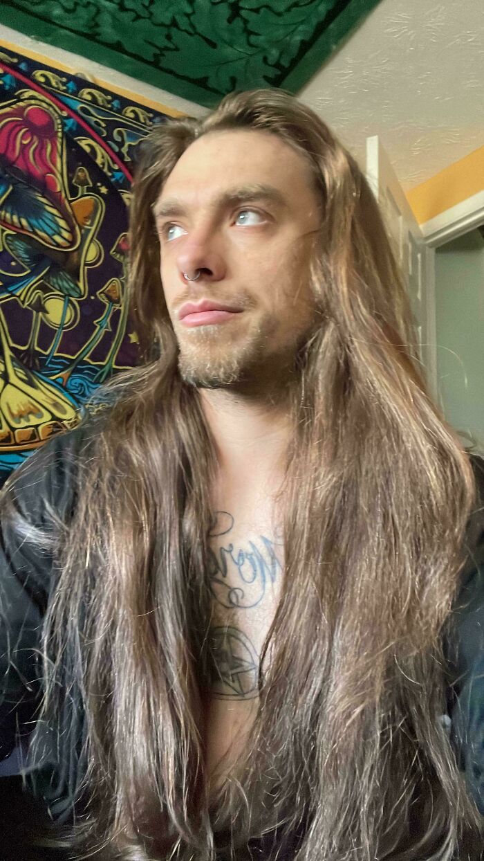 A man with long, straight brown hair looks away from the camera, showcasing his ridiculously amazing long hair.