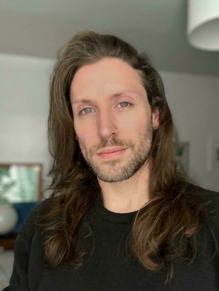 A man with amazing long hair, a nose ring, and a beard, wearing a black sweater.