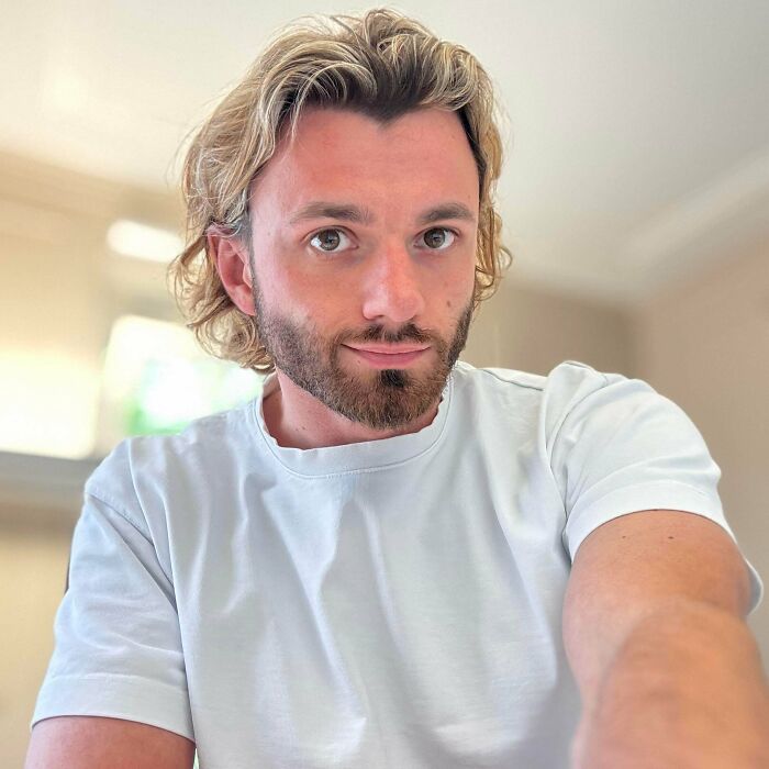 A man with amazing long hair, light blonde and wavy, looking at the camera.