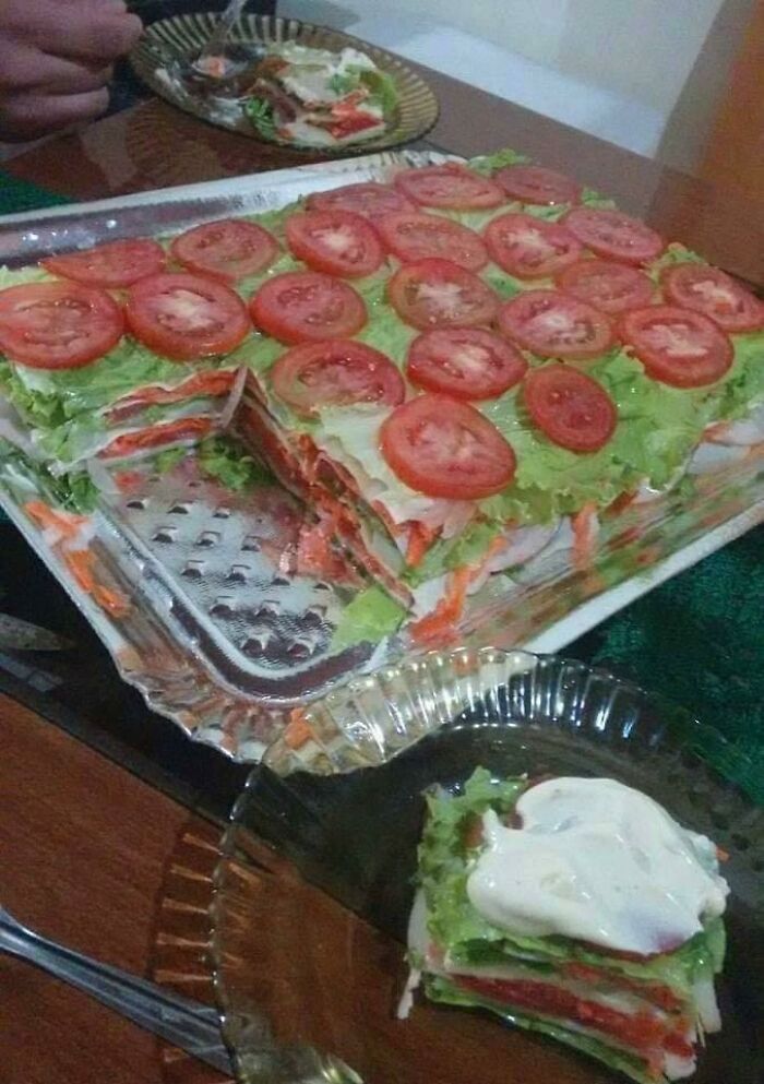 Layered sandwich cake with tomato slices and vegetables as garnish