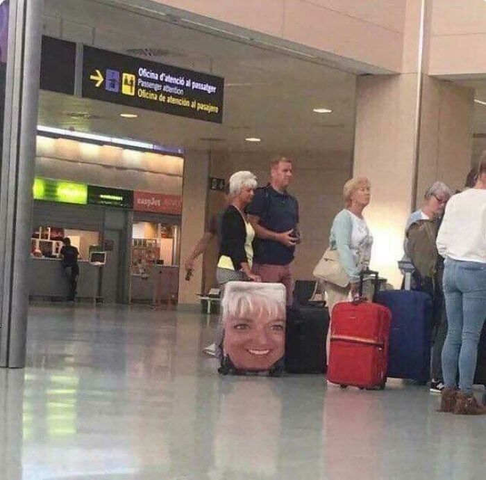Suitcase with a large smiling face print in airport scene showing craftsmanship wasted on weird concept