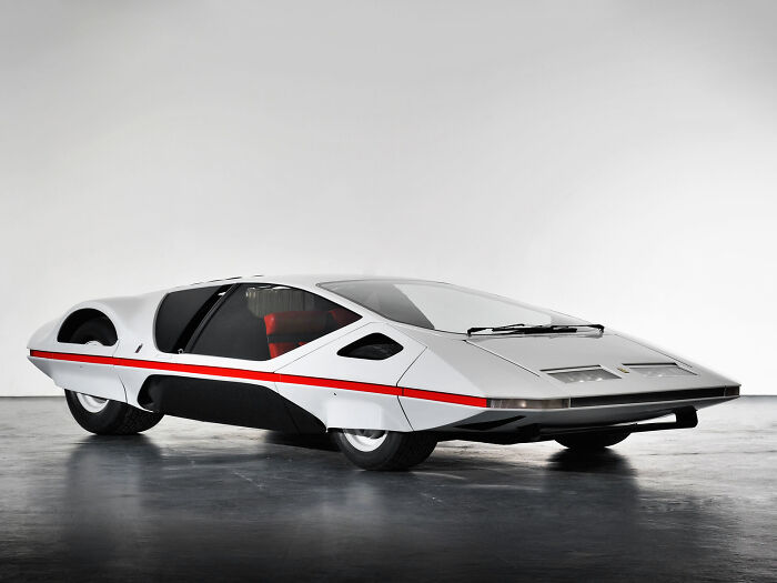 White streamlined retrofuturistic concept car with red stripe on display floor