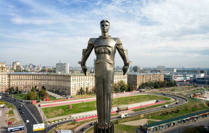 Retrofuturism large metal statue of man in futuristic armor overlooking city and roads