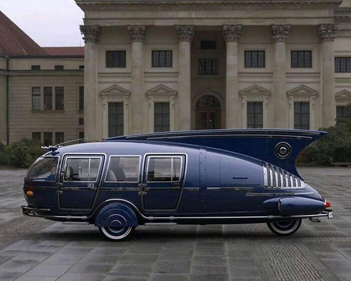 Retrofuturism unique retro futuristic black vehicle with rounded design outside building