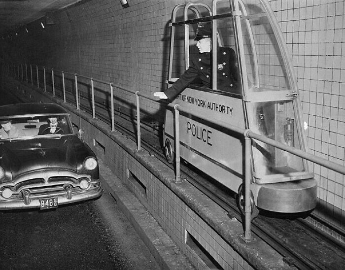 Retro police patrol in a futuristic small one-person pod near vintage car in tunnel