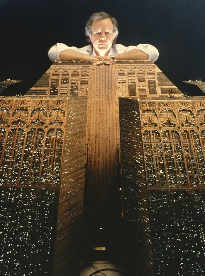 Retrofuturism image of man with model of futuristic city building with lights