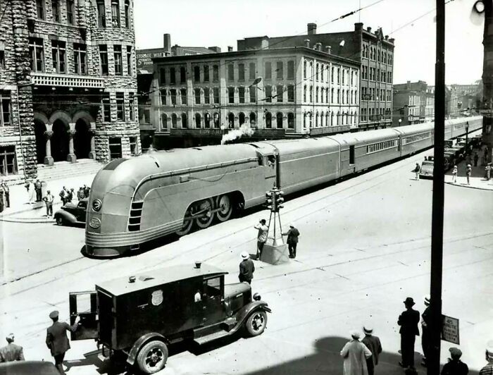 Vintage retrofuturism streamlined train moving through a city street from early 20th century