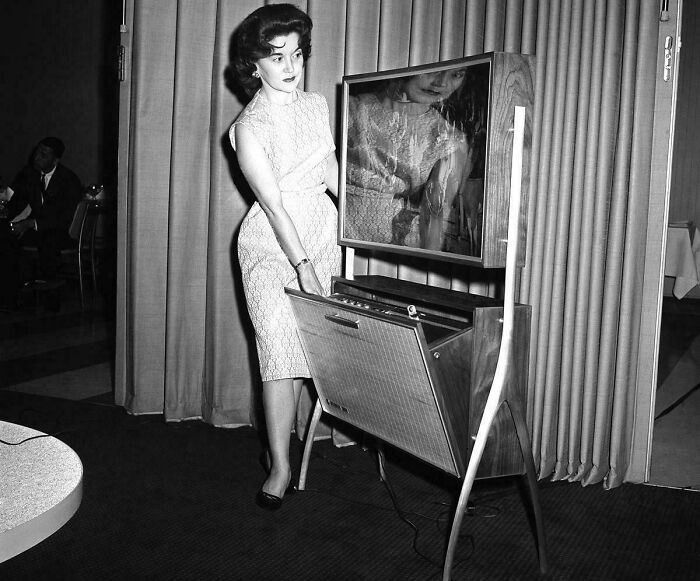 Retrofuturism 1960s woman demonstrating a retro television and radio cabinet