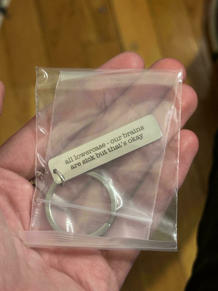 Hand holding keychain in plastic bag with a sign using lowercase letters showing humorous failed instructions.