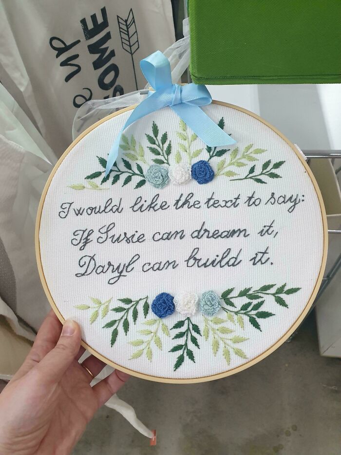 Embroidery hoop with floral design and handwritten text showing a funny failure to understand instructions misprint.