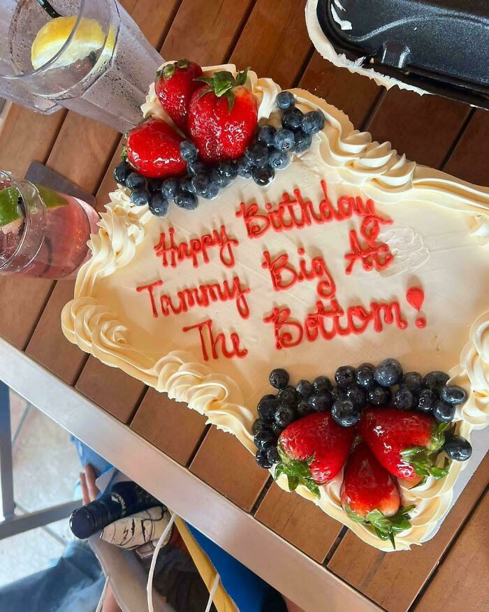 Birthday cake with strawberries and blueberries showing a hilarious misprint in the icing message.