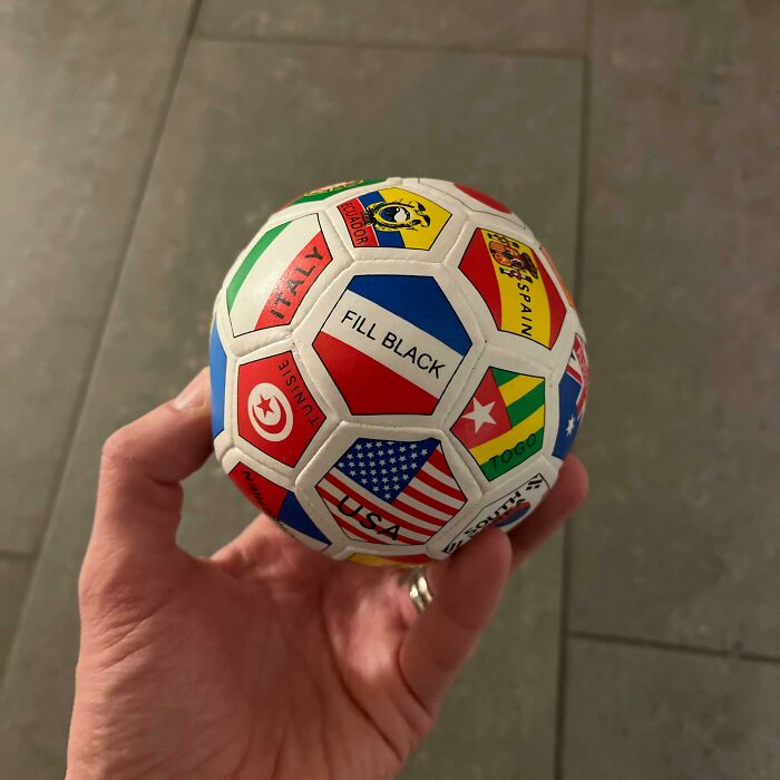 Hand holding a soccer ball with country flags, including a misprint labeled fill black, showing hilarious misprints.