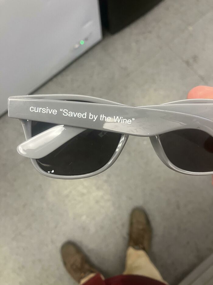 Gray sunglasses with the phrase saved by the wine printed on the arm showing a hilarious misprint fail.