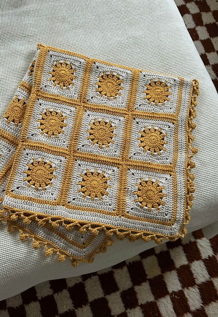 A beautifully crocheted blanket featuring square granny motifs with yellow sunburst centers, showcasing awesome handmade craft.