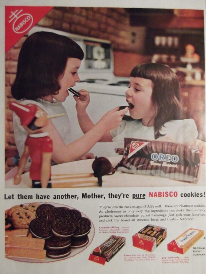 Two young girls in a retro kitchen sharing Nabisco Oreo cookies from a vintage advertisement.
