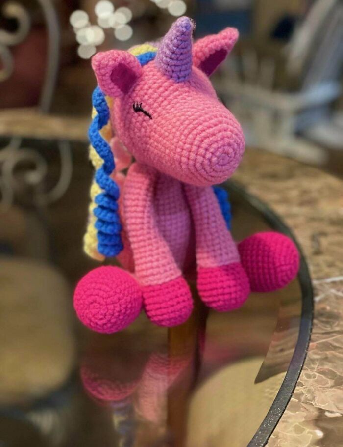 A charming pink crocheted unicorn with blue and yellow mane, showcasing an awesome crocheted item that wowed the internet.