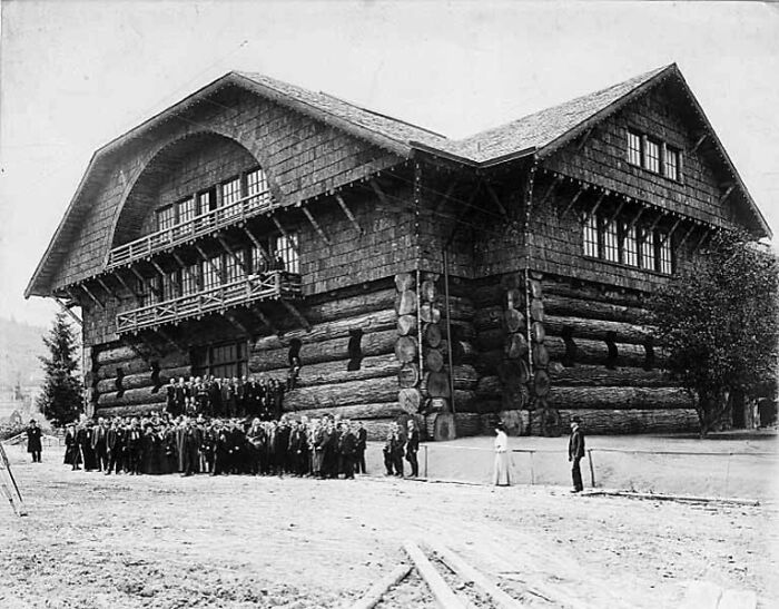 Large historic log building with a group of people gathered outside, showcasing interesting buildings lost over time.