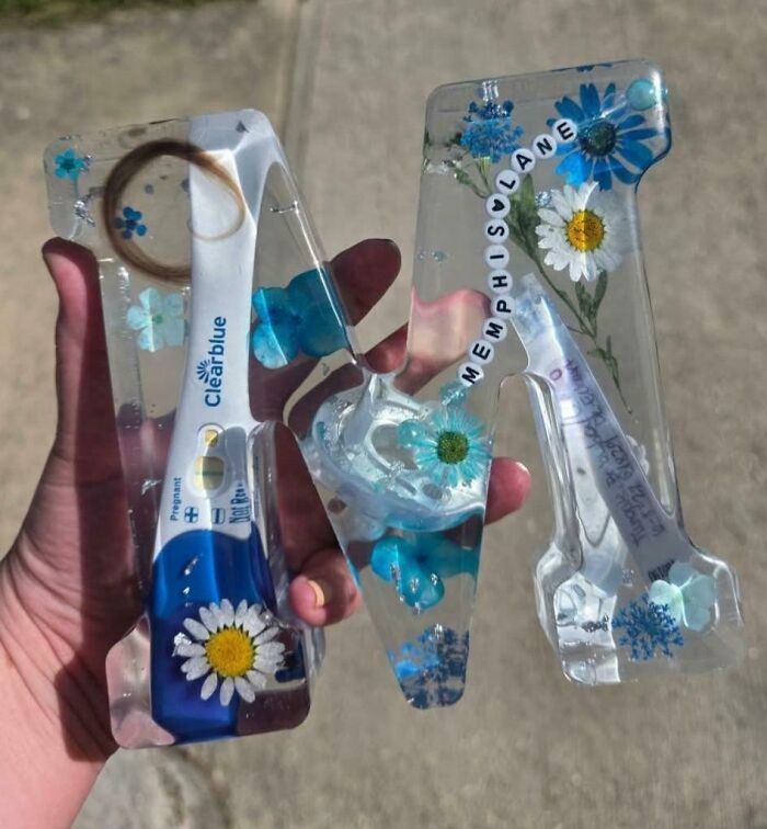 Clear resin DIY project embedding flowers and pregnancy test sticks, showcasing a deeply cursed DIY project result.