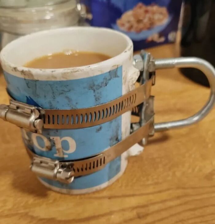 Coffee mug with a DIY handle made from metal clamps, showing a deeply cursed and impractical project setup.
