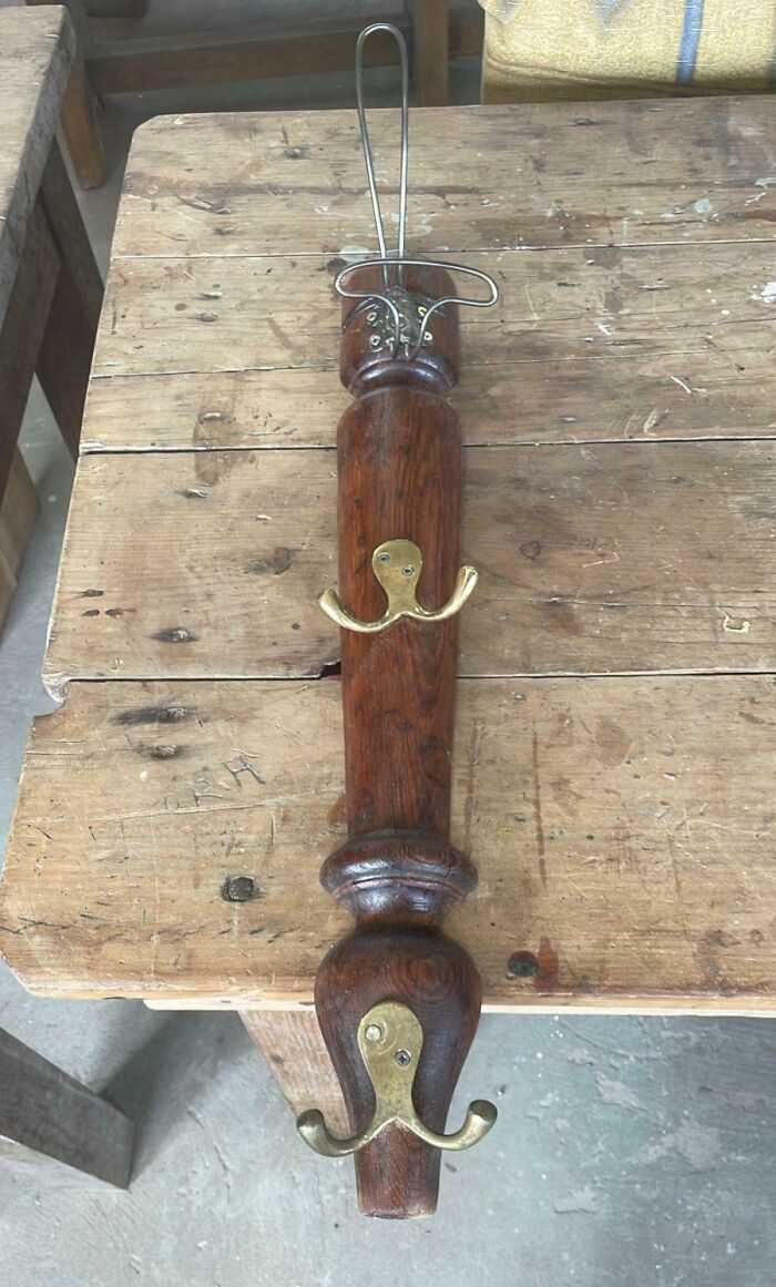 Wooden DIY project coat rack with hooks and metal wire on a worn wooden table showing a deeply cursed design.