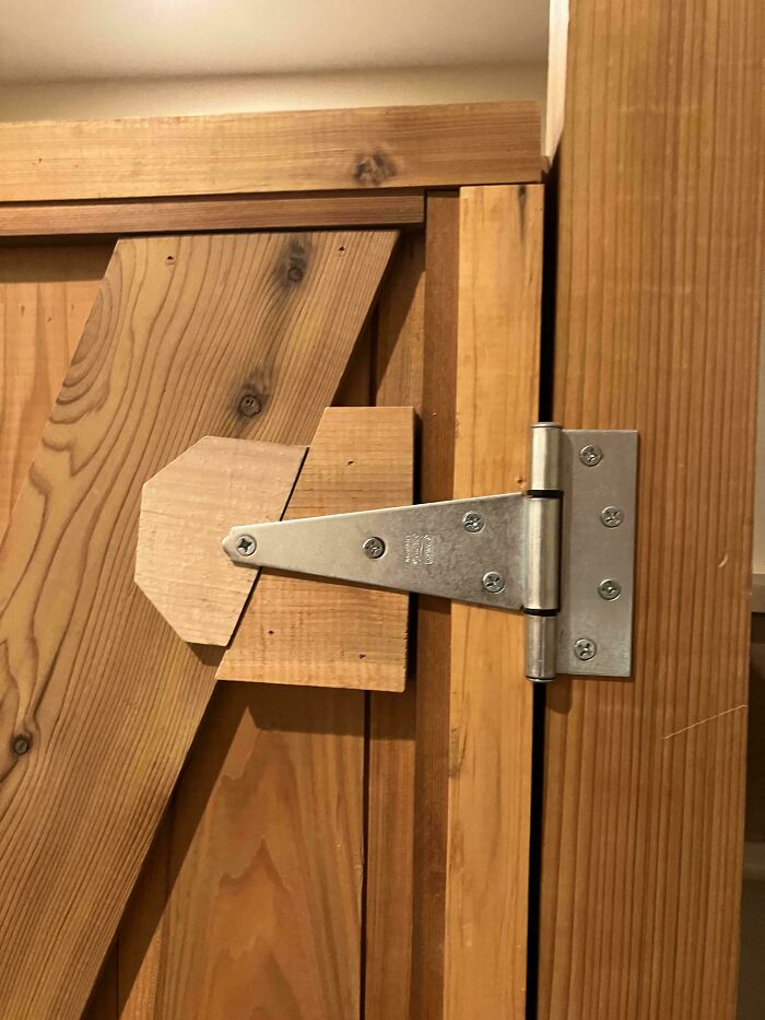 Wooden door hinge with oddly shaped wooden support, a DIY project that ended up deeply cursed and poorly executed.