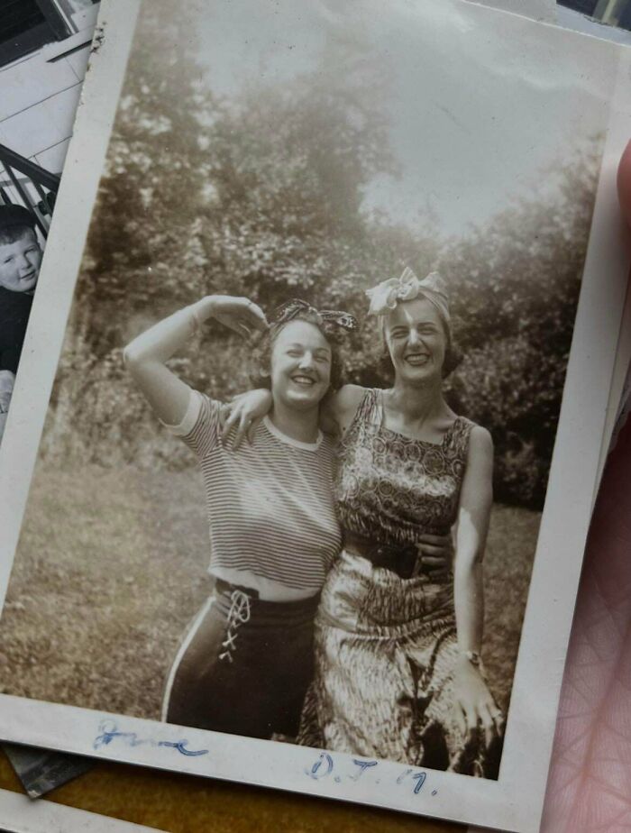Two smiling women in headscarves embrace outdoors in this candid old photo from generations ago.