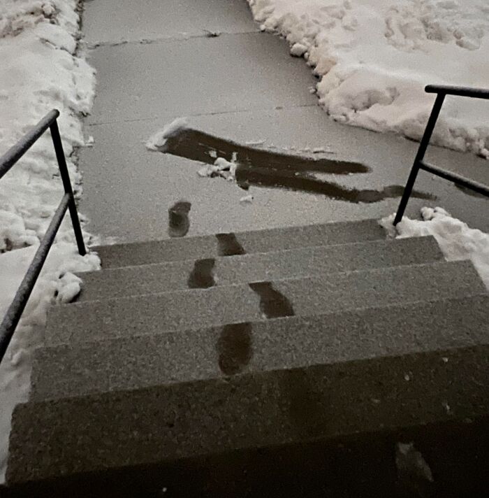 Footprints in the snow showing a funny and confusing path on icy steps and sidewalk in a humorous photo.