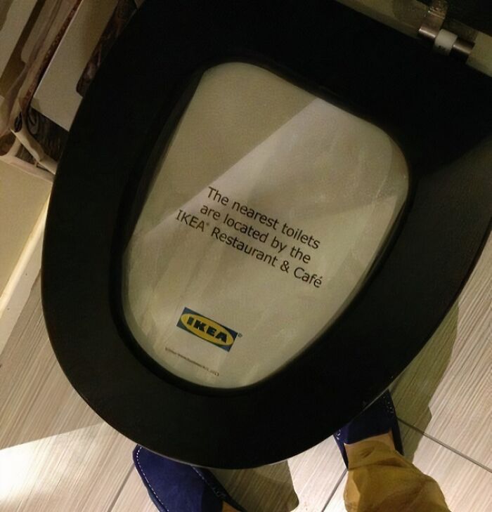 Toilet seat with a sign inside directing to nearest toilets by the IKEA Restaurant & Café, a funny photo for quick laughs.