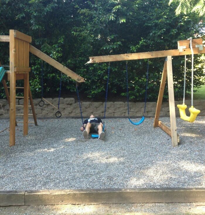 Person lying flat on a broken swing set, capturing a funny moment from a collection of funny photos that say it all.