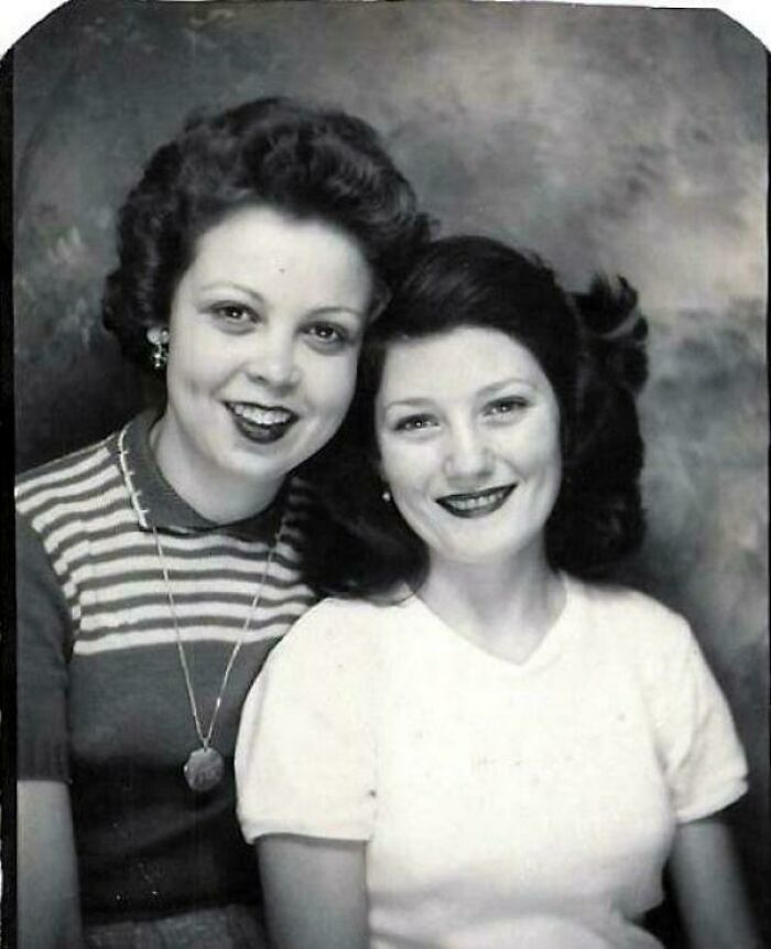 Candid old photos: Two smiling women with dark lipstick posing closely together for a portrait.