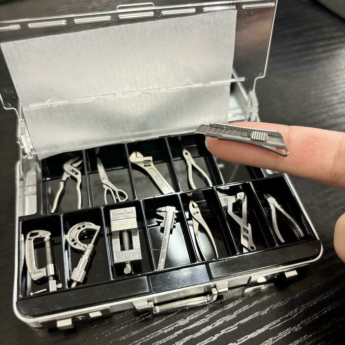 Miniature precision tools kit displayed in a small case with a finger holding a tiny cutter, showcasing interesting tools.