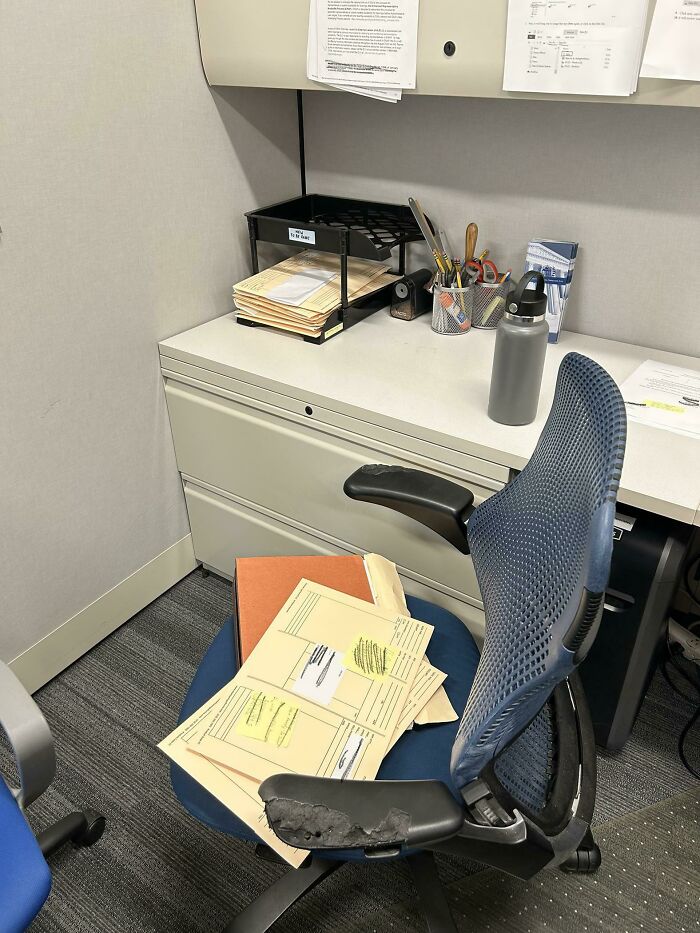 Office chair with worn armrest and scattered files, showing signs of laziness in a cluttered workspace environment.