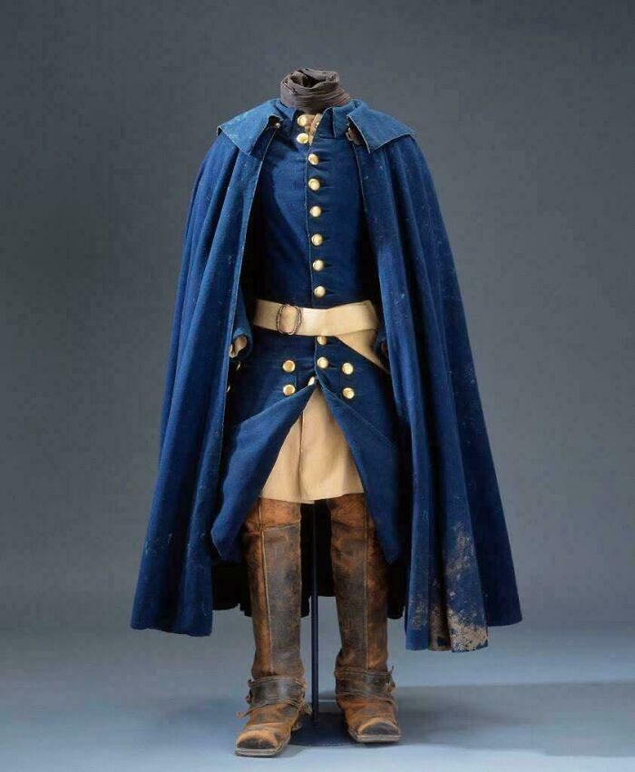 Antique military uniform with blue coat, beige pants, and worn brown boots, showcasing almost perfectly preserved historical details.