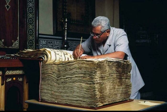 Man examining an almost perfectly preserved antique book with intricate calligraphy, highlighting historical secrets.