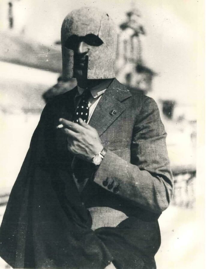 Man wearing an antique metal helmet and a suit, holding a cigarette, showcasing almost perfectly preserved historic attire.
