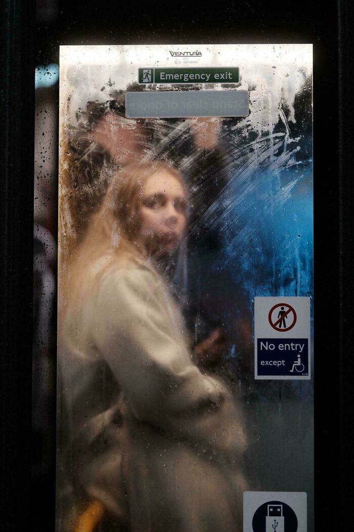 A reflective woman seen through a foggy glass door, creating an Accidental Renaissance aesthetic.