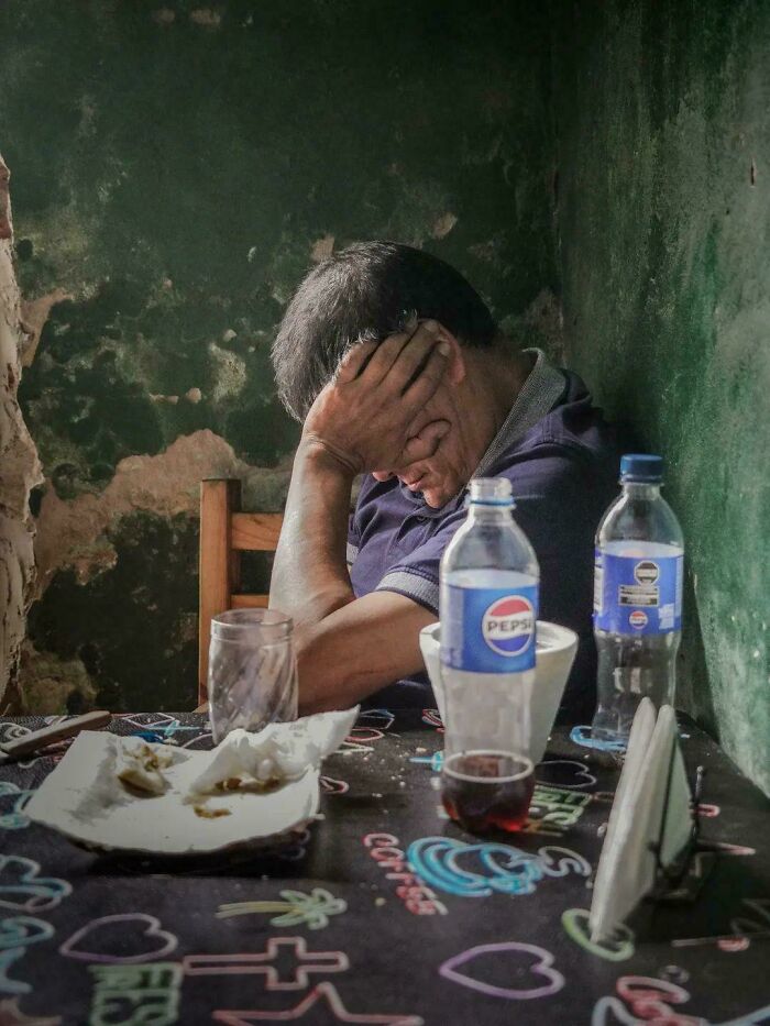 Tired man sitting at a table with his head in his hand, a raw Accidental Renaissance moment.