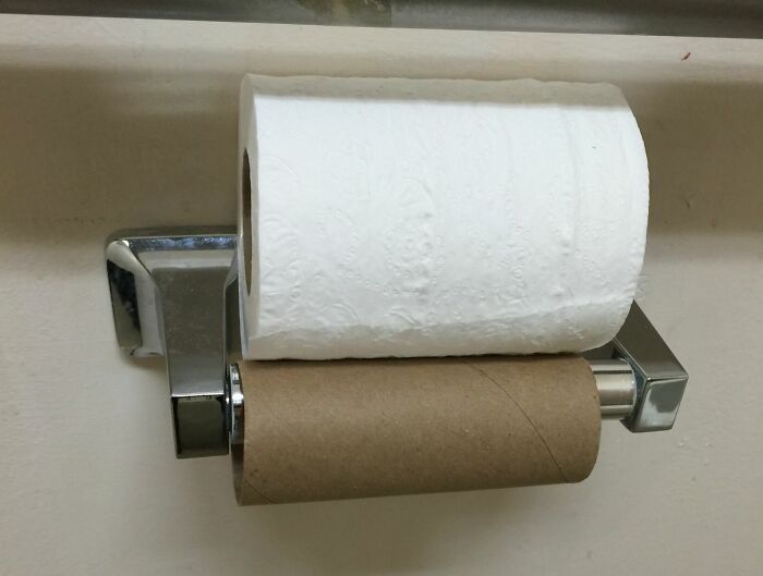 Toilet paper roll placed on top of an empty one on holder, illustrating extreme laziness and lack of effort.
