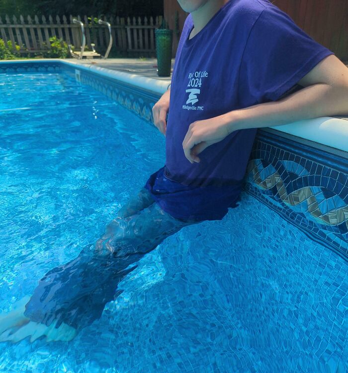 Person sitting lazily at the edge of a pool with legs submerged in water, enjoying a relaxing day off.