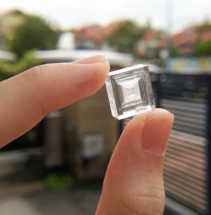 Hand holding a clear crystal with geometric patterns in nature pics showcasing interesting and beautiful details.