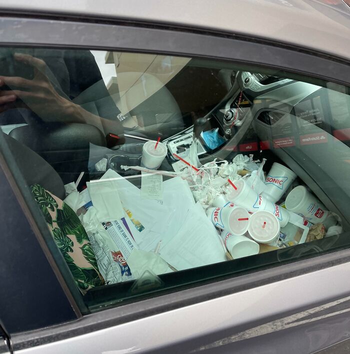 Car interior filled with trash and empty Sonic cups, showcasing extreme laziness and clutter in a vehicle.