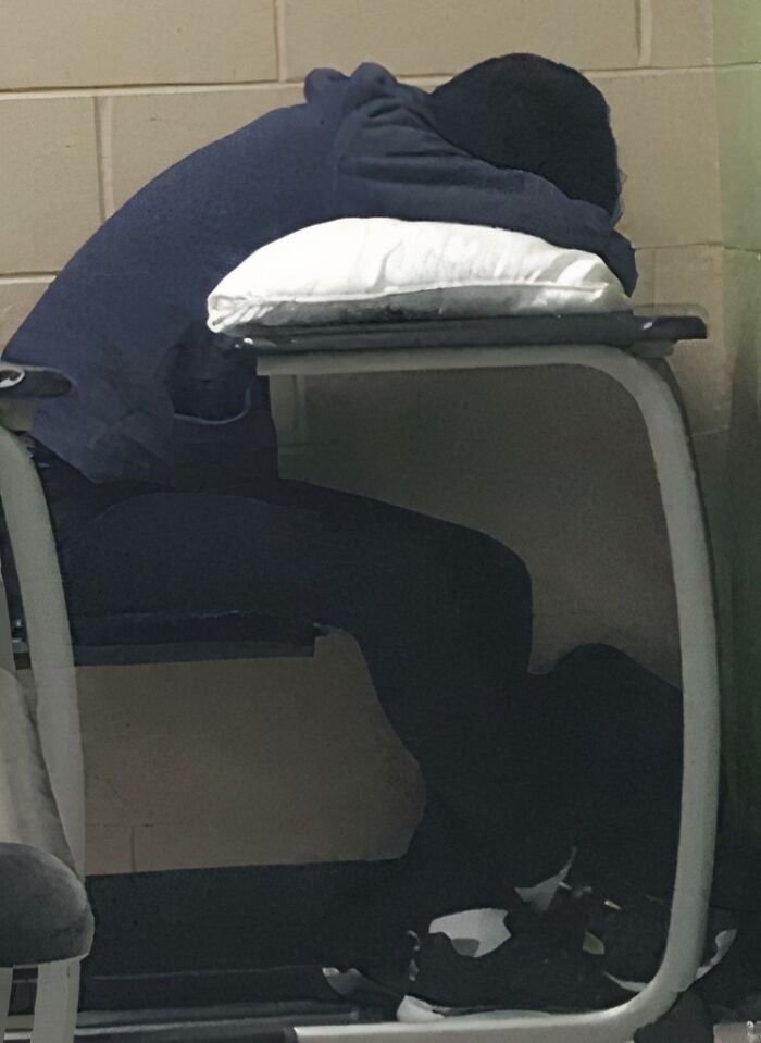 Person resting head on a pillow placed on a desk, illustrating laziness and taking a day off in a casual setting.