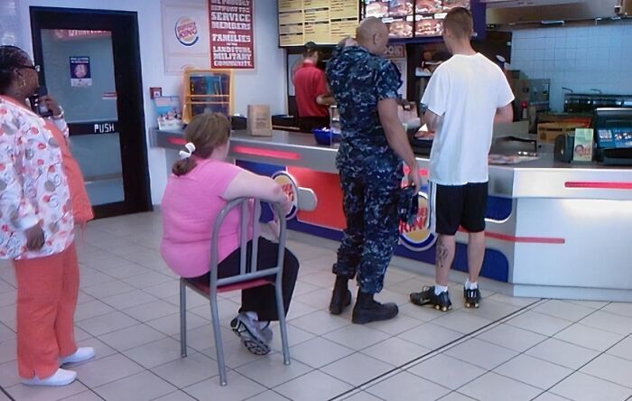 Woman sitting on a chair in line at a fast-food restaurant, illustrating people who are so lazy they might inspire day off ideas.